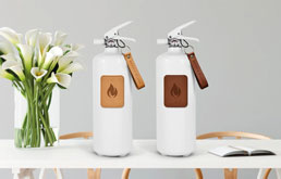 Stilfulde hvide brandslukkere fra Nordic Flame placeret på et bord med blomster